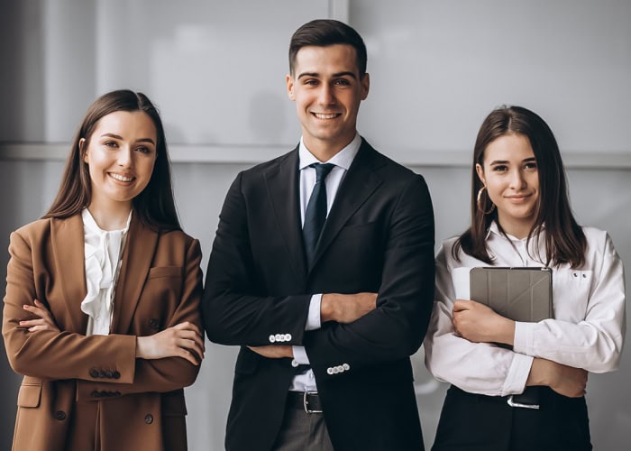 Three business professionals standing together in a modern office, engaged in conversation and collaboration.